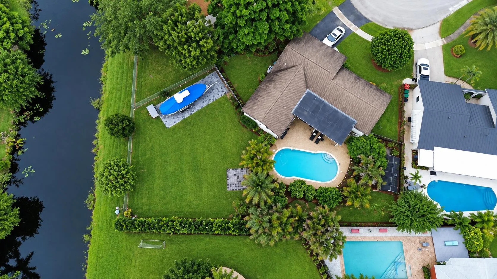 Expansive green lawn with mature trees, private swimming pool, and dedicated boat storage area