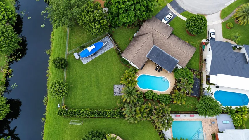 Expansive green lawn with mature trees, private swimming pool, and dedicated boat storage area