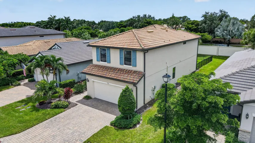 Exterior featuring a concrete tile roof, stucco siding, and a paver driveway