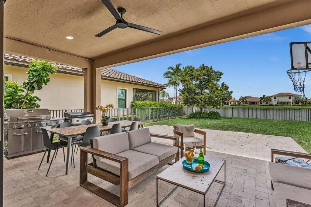 Expansive covered patio featuring a paver flooring, outdoor ceiling fan, and built-in grill station