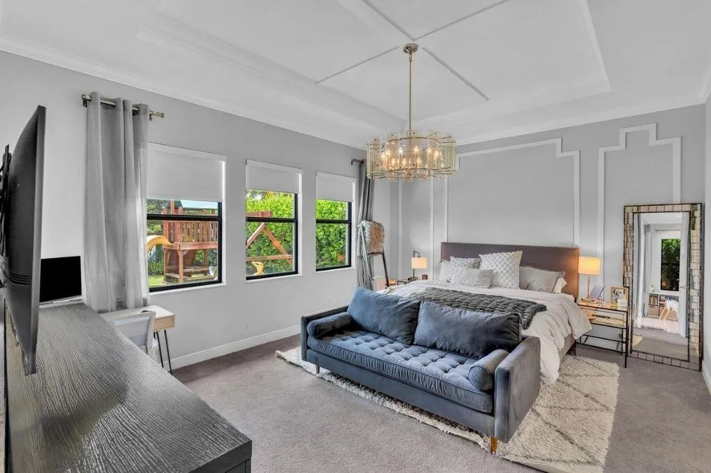 Spacious room featuring a tray ceiling with crown molding, a decorative chandelier, and three large windows
