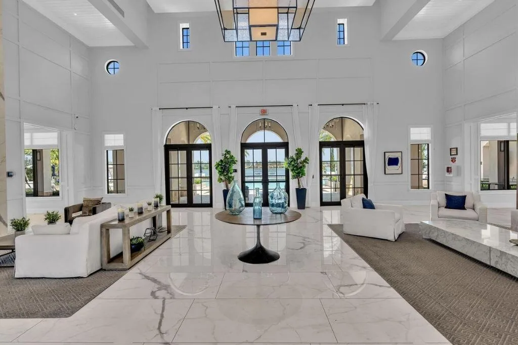 Grand foyer featuring a high ceiling, polished marble-finish flooring, arched glass-paned doors, and transom windows