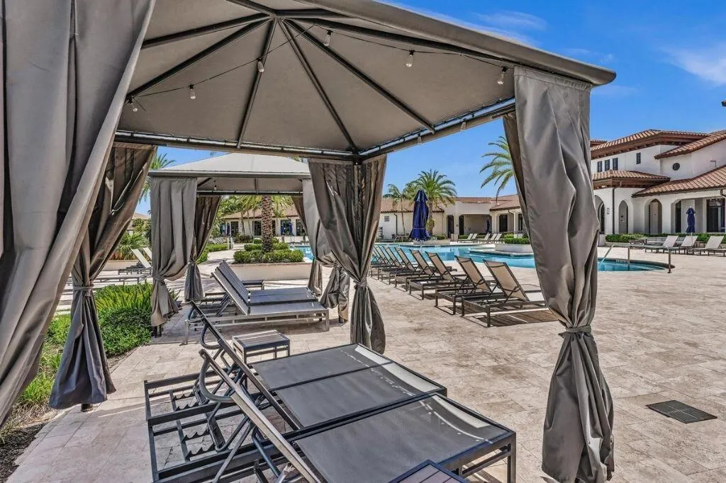Private cabana with string lighting and lounge seating overlooking a resort-style pool deck