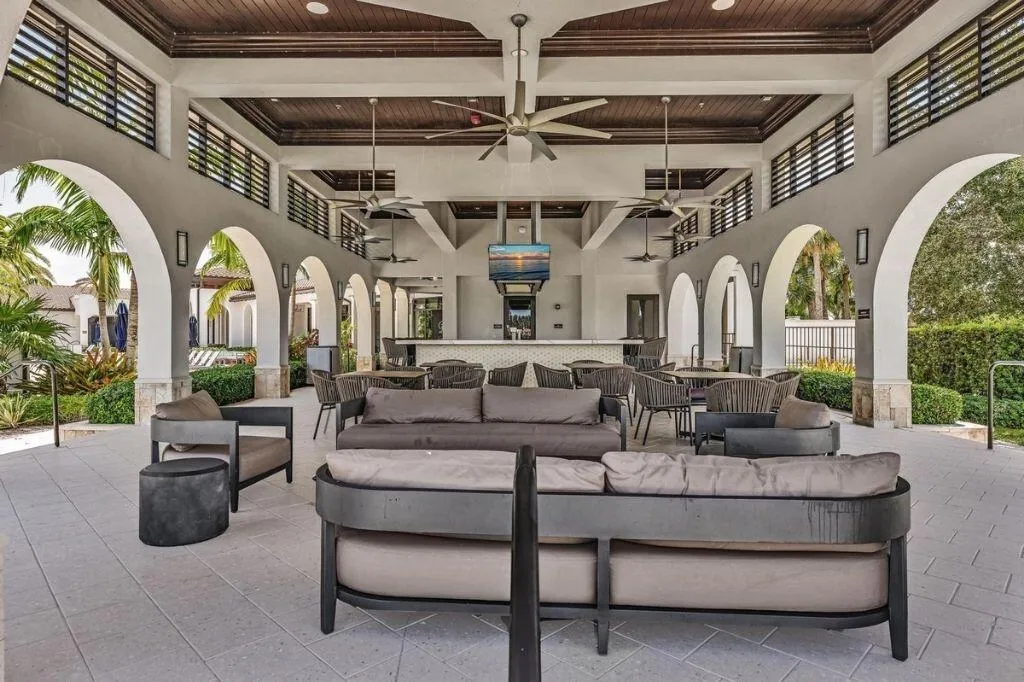 Open-air covered patio area featuring a high vaulted wood-finish ceiling, multiple ceiling fans, and arched doorways