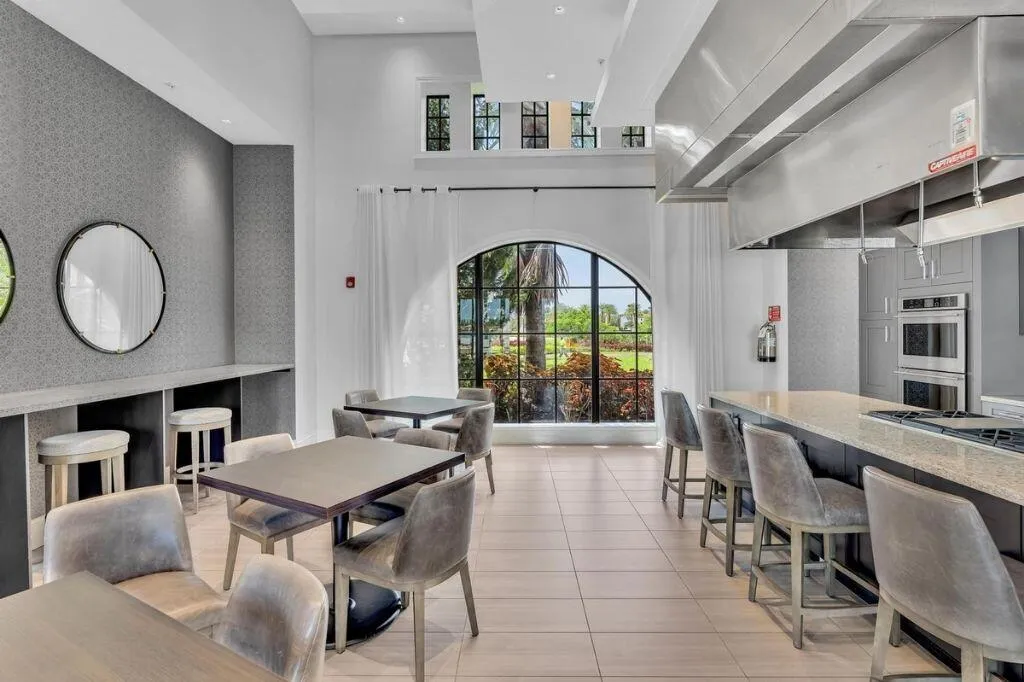 Spacious common area featuring a professional-grade kitchen, an oversized island with bar seating, and a large arched window