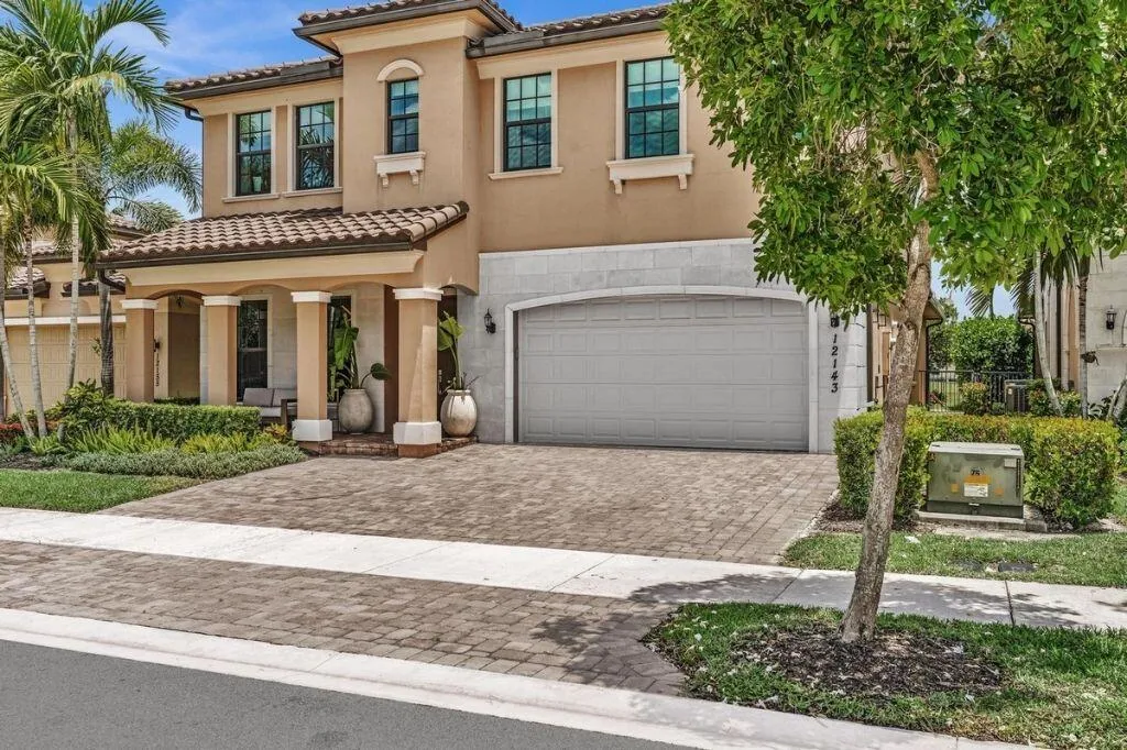 Two-story stucco residence featuring a tile roof and decorative columns at the front entry