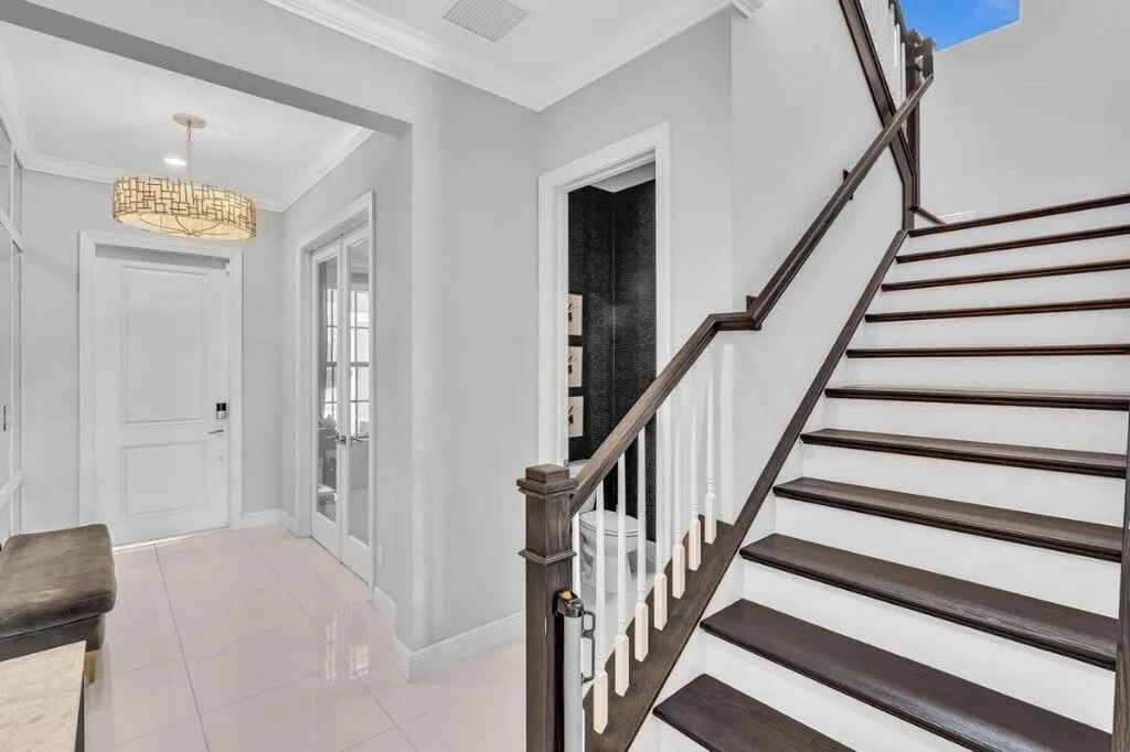 Grand staircase featuring dark wood treads and handrails with white risers and balusters