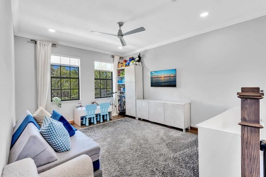 Bright room featuring two large windows with black framing, recessed lighting, and a ceiling fan