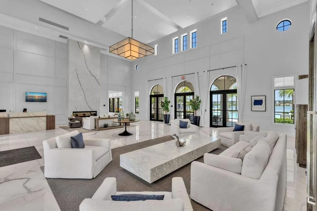 Grand lobby featuring a towering fireplace with large-format veined slab surround, high ceilings with recessed lighting, and expansive arched doorways