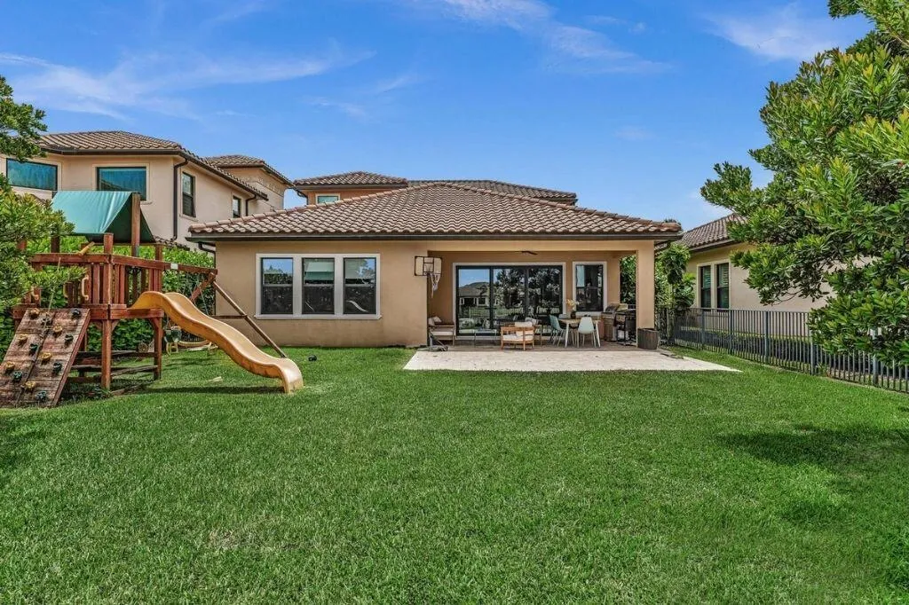Expansive grassy yard featuring a covered patio, tiled roof, and stucco exterior