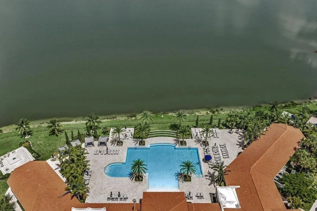 Resort-style pool area featuring a large swimming pool, expansive paved patio, and multiple lounge seating areas