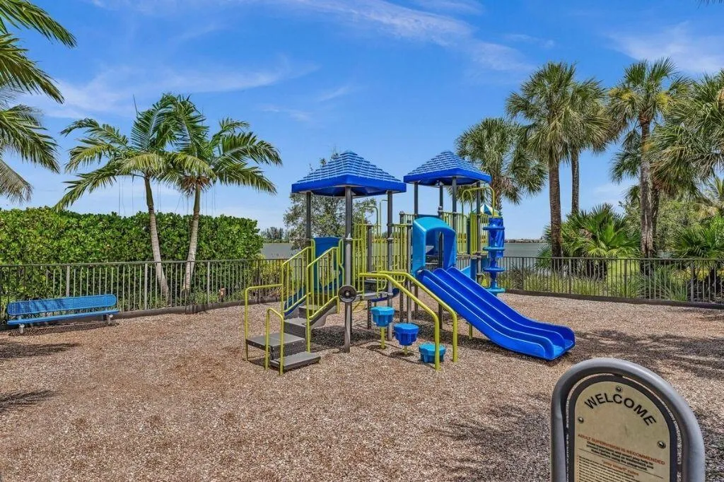 Recreational playground with blue and yellow play structures, a slide, and a bench, set on a wood chip surface