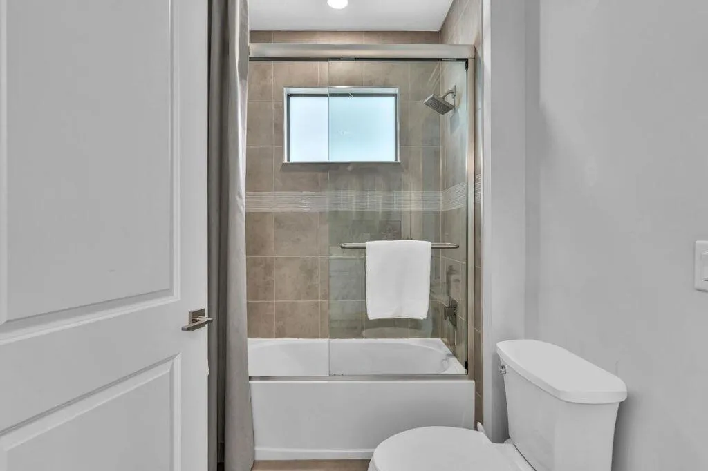 Bathroom featuring a white bathtub, glass shower enclosure, and tiled surround