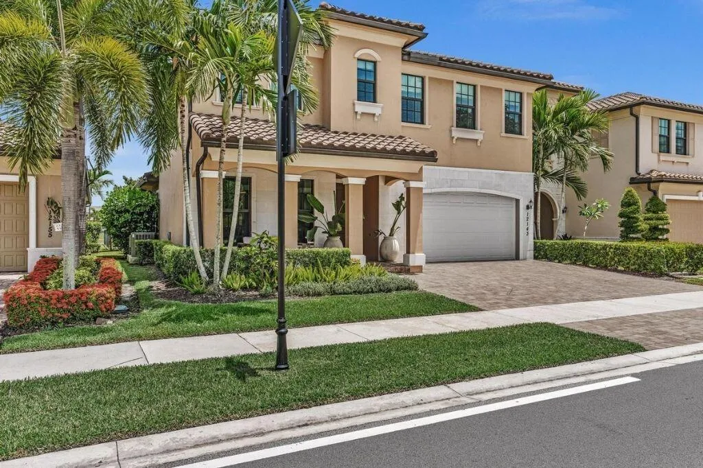 Two-story residence featuring a stucco exterior, barrel tile roof, and a paver driveway