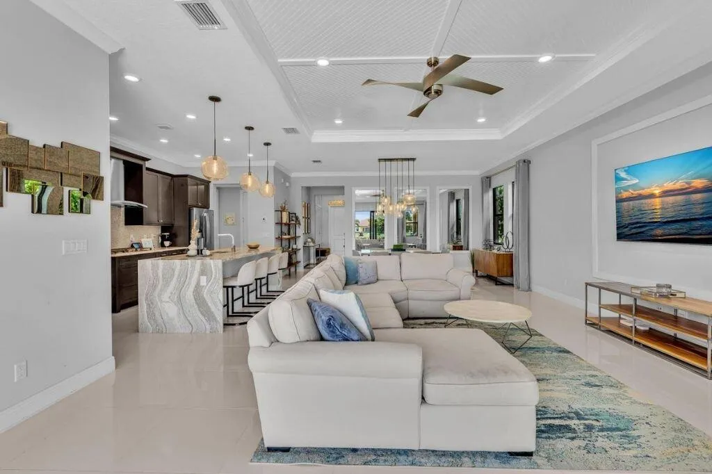 Open-concept living space featuring sleek tile flooring and a tray ceiling with a contemporary ceiling fan