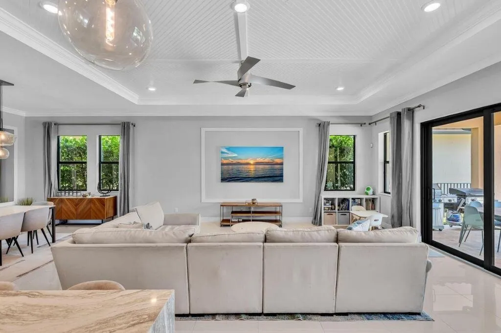 Spacious open-concept living area featuring a tray ceiling with beadboard detail, recessed lighting, and a ceiling fan
