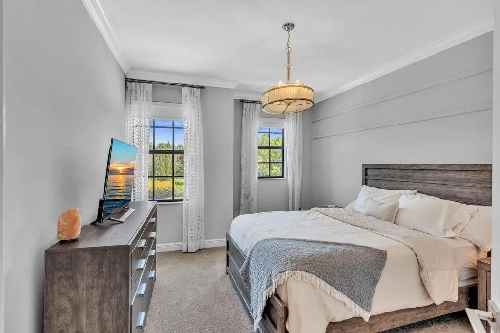 Light gray walls with crown molding, two windows with gridded panes, and a decorative ceiling light fixture