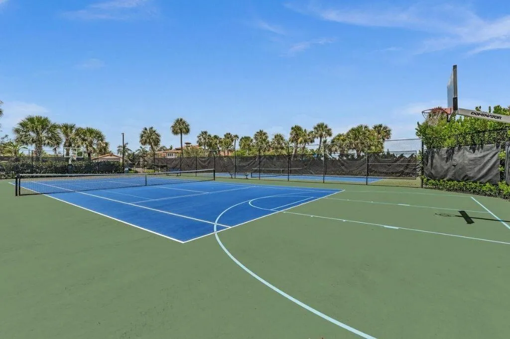 Multi-sport court featuring a blue tennis court and green surrounding surface