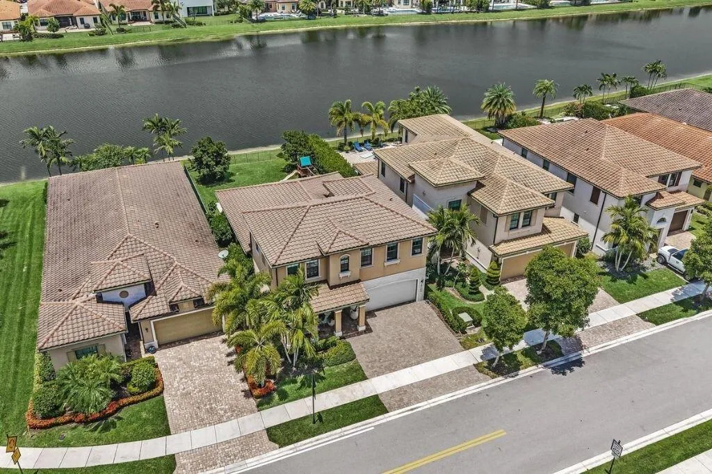 Tile-roofed residence featuring a paved driveway, a two-car garage, and mature landscaping