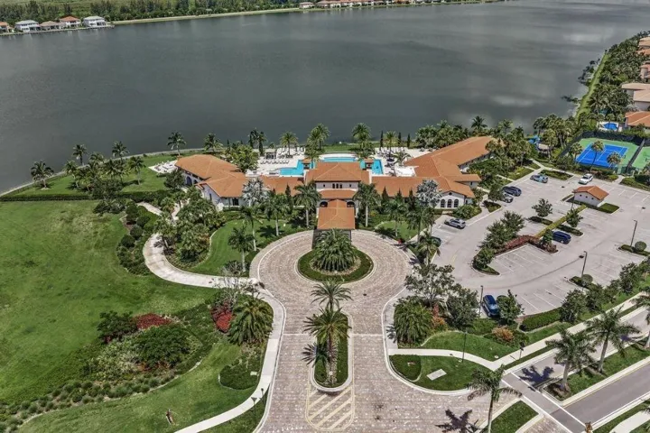 Expansive waterfront property featuring a large central building with a terracotta roof, multiple swimming pools, two tennis courts, and a circular paved driveway