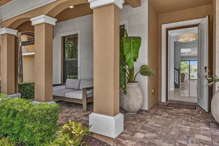 Covered front entry featuring a paver stone patio, decorative columns, and a solid wood front door