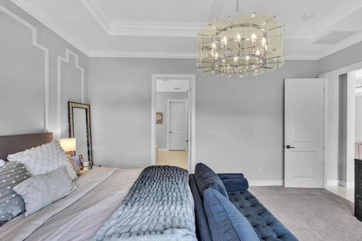 Tray ceiling with crown molding, decorative wall molding, contemporary chandelier, and two-panel interior doors