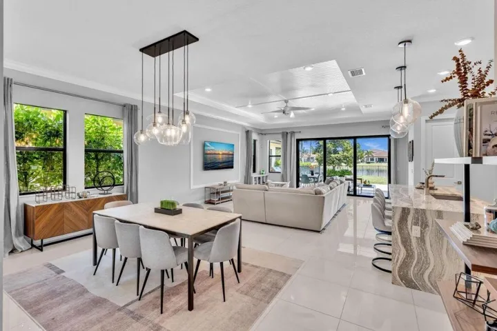 Open-concept living area with large format tile flooring and tray ceiling