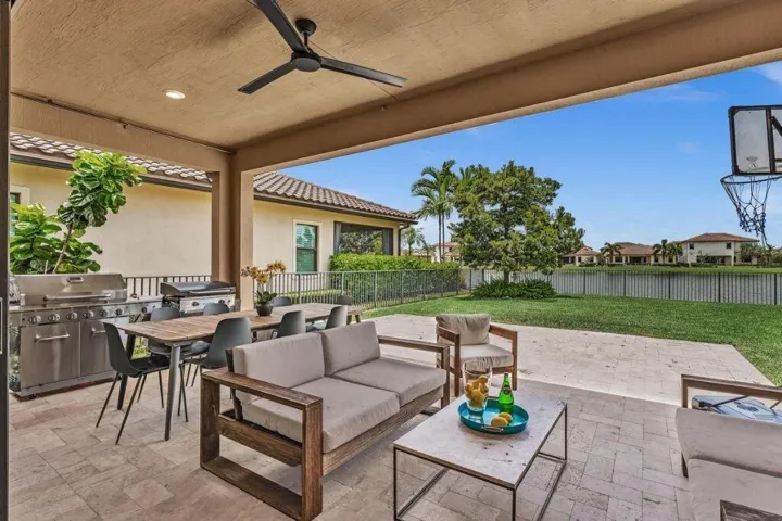 Expansive covered patio featuring a paver flooring, outdoor ceiling fan, and built-in grill station