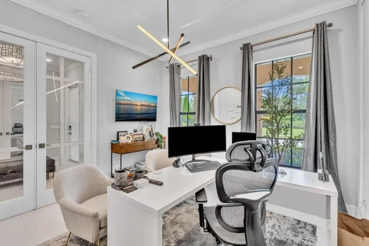 Bright room featuring double French doors with glass panels, a modern linear chandelier, and two large windows with dark frames