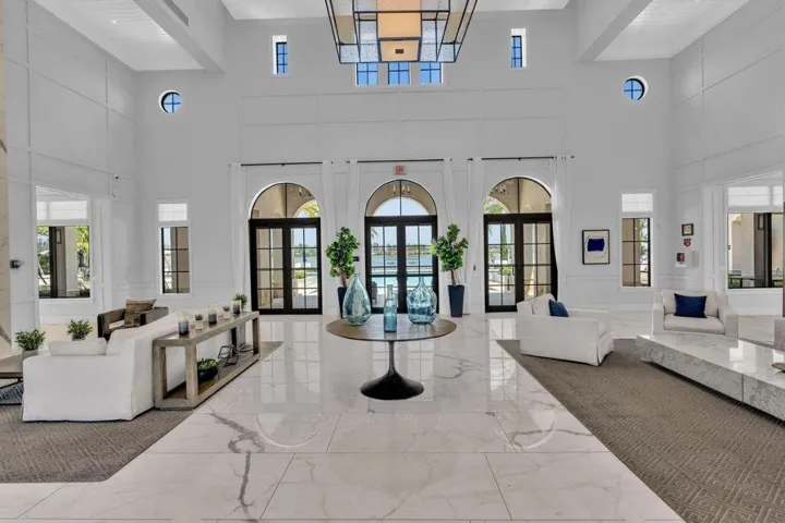 Grand foyer featuring a high ceiling, polished marble-finish flooring, arched glass-paned doors, and transom windows