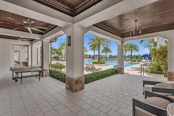 Covered outdoor patio featuring tiled flooring, decorative wood-paneled ceiling, recessed lighting, and ceiling fans