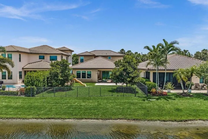 Waterfront property featuring a stucco exterior, tile roofing, and a fenced backyard with a pool