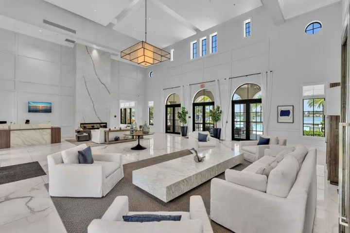 Grand lobby featuring a towering fireplace with large-format veined slab surround, high ceilings with recessed lighting, and expansive arched doorways