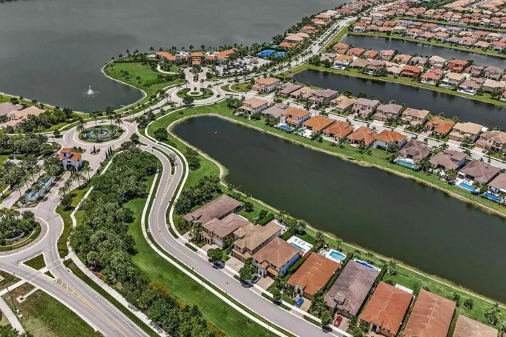 Aerial perspective of a planned residential community featuring numerous waterfront properties, multiple large water bodies, and extensive green spaces