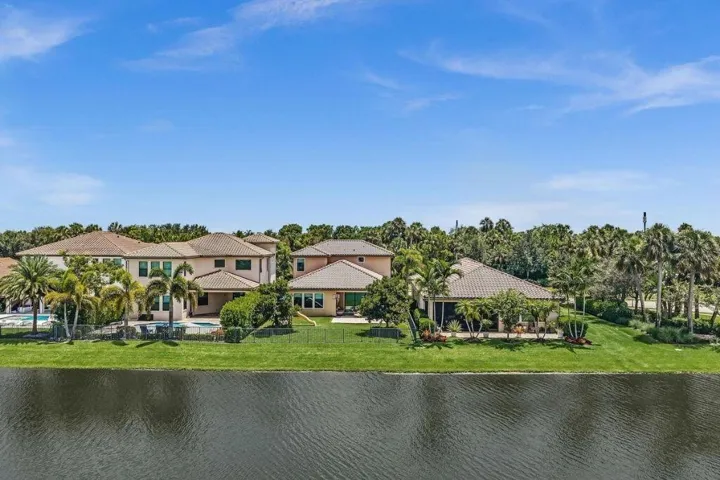 Waterfront property featuring a private swimming pool, extensive patio space, and mature palm landscaping