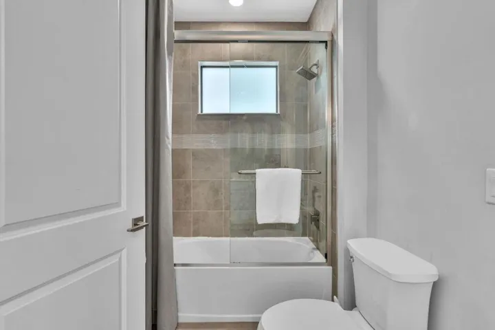 Bathroom featuring a white bathtub, glass shower enclosure, and tiled surround