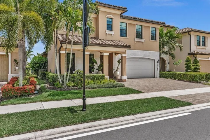 Two-story residence featuring a stucco exterior, barrel tile roof, and a paver driveway