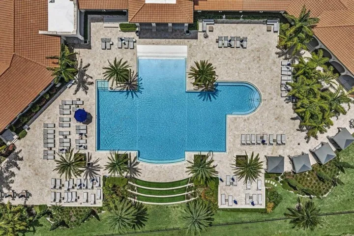 Expansive aquatic area featuring a multi-section swimming pool with integrated steps, surrounded by extensive light-toned paving