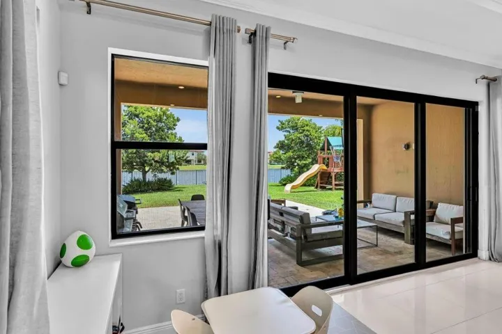 Stacable Sliding glass doors opening to a covered patio featuring a tiled surface and a grassy yard