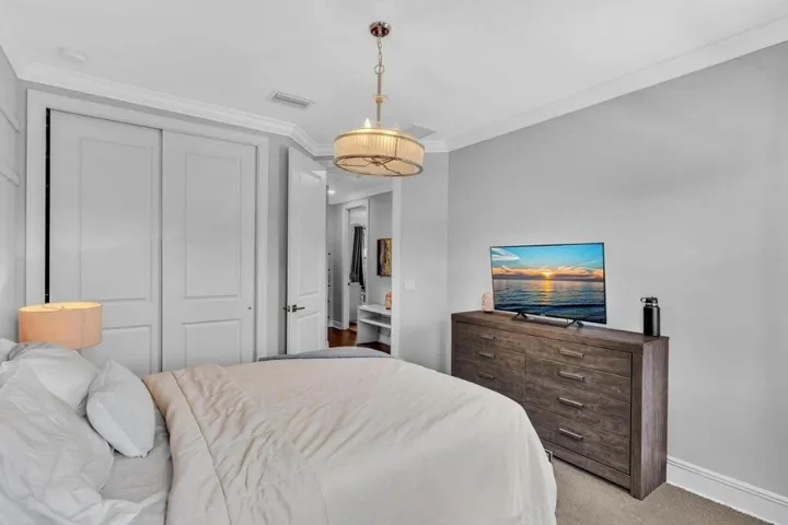 Bedroom featuring a built-in closet with double panel doors, crown molding, a ceiling-mounted drum light fixture, and light gray wall paint