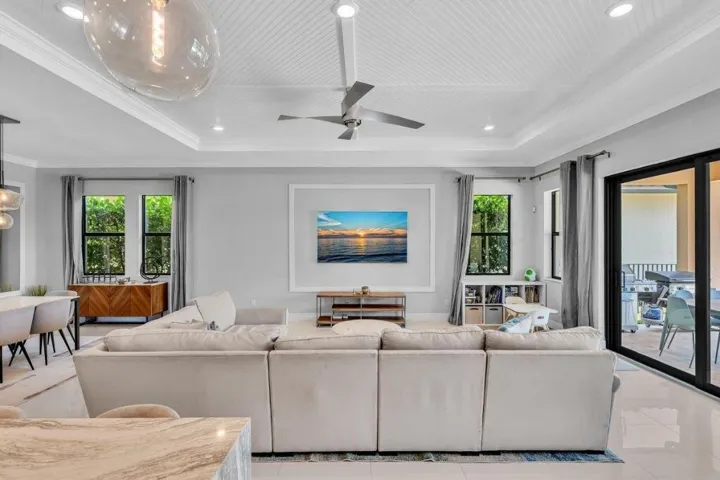 Spacious open-concept living area featuring a tray ceiling with beadboard detail, recessed lighting, and a ceiling fan
