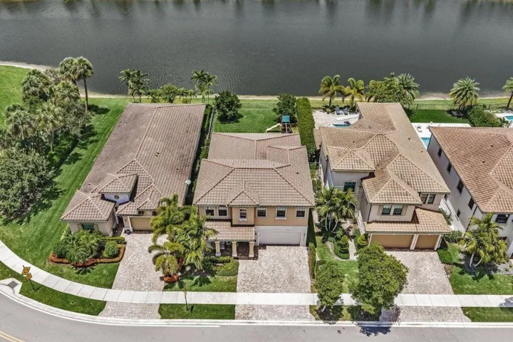 Aerial perspective showcasing a canal-front property with a tile roof and attached garage