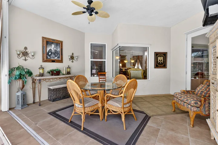Tiled flooring with a decorative area rug, corner window, ceiling fan, and access to an interior space