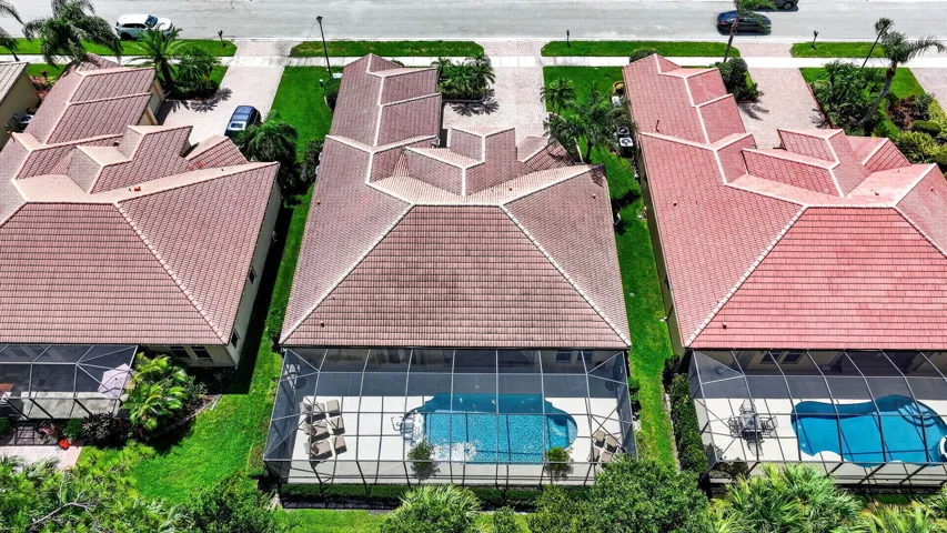 Tile roof, screened pool enclosure, paved driveway, landscaped yard, and mature vegetation