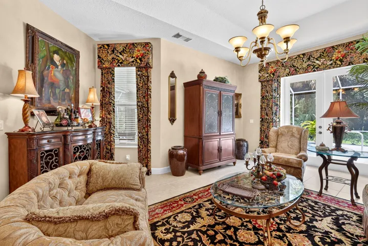 Ornate chandelier, French doors, window with blinds, and tile flooring