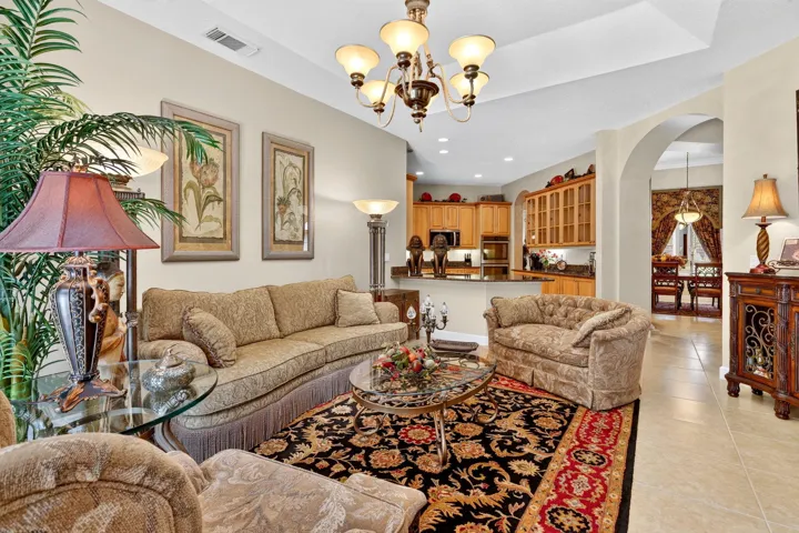 Tray ceiling, archway, tile flooring, recessed lighting, and kitchen with wood cabinetry