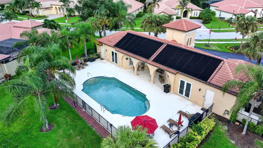 Expansive pool deck with a free-form community swimming pool, integrated solar panels, and a tiled roof