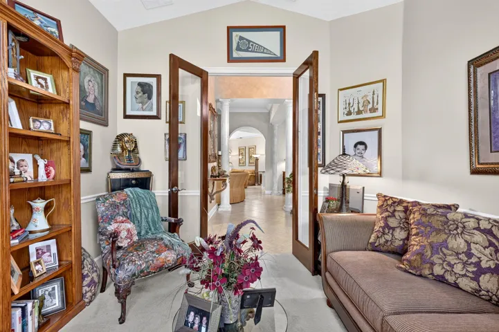 Vaulted ceiling with crown molding, double French doors, and neutral wall paint