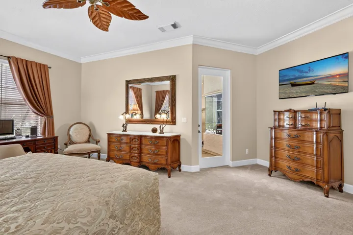 Crown molding, ceiling fan, carpet flooring, and a glass-paneled door
