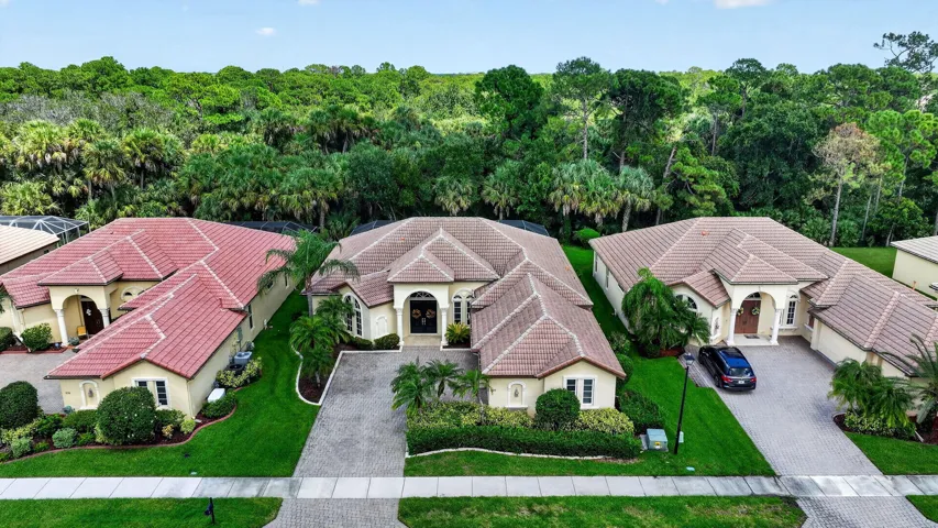 Exterior features a tile roof, paved driveway, arched entry, and extensive landscaping